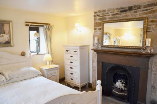een slaapkamer met een open haard, een spiegel en een bed bij Bothy in Alston