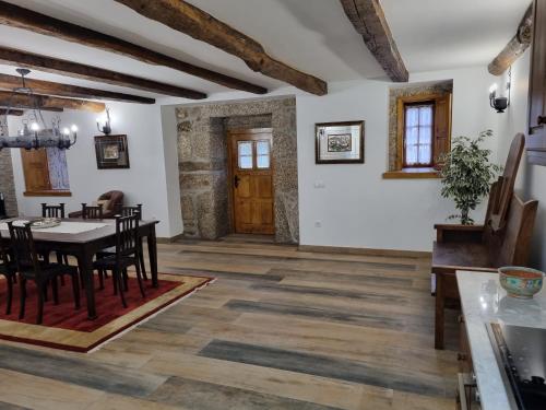 a dining room with white walls and wooden floors and a table and chairs at Casa das Lages in Vieira do Minho