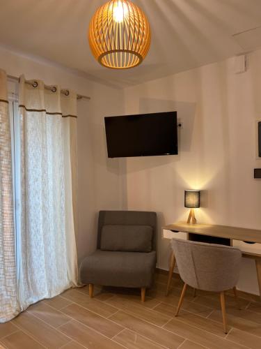 a living room with a chair and a desk and a television at Calm Joy & J - New Bird in Ermoupoli