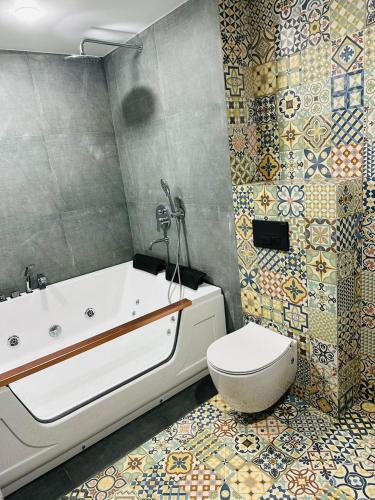 a bathroom with a tub and a toilet and tiles at villa gardens in K'obulet'i