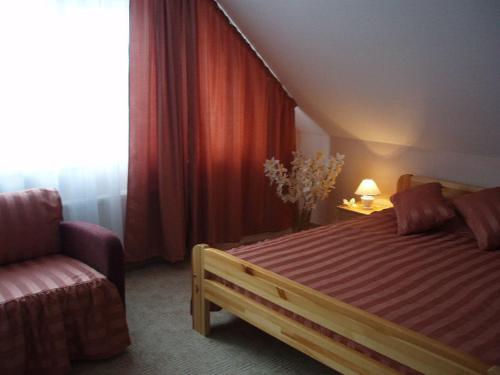 a bedroom with a bed and a chair and a window at Viesu Nams Vecupe in Birzgale
