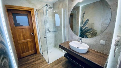 a bathroom with a sink and a shower with a mirror at Apartamenty w Maniowach in Maniowy