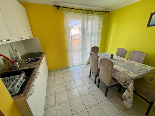 a kitchen with a dining room table and yellow walls at Apartments Mikulić in Rogoznica