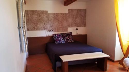 - une petite chambre avec un lit et un banc dans l'établissement Maison de caractère La Calade, à Rochecolombe