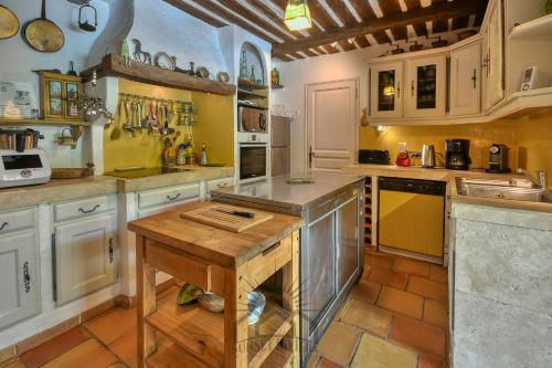 une cuisine avec des armoires blanches et une table en bois dans l'établissement SERENITY Villa for 8 By Sunset, à Grasse