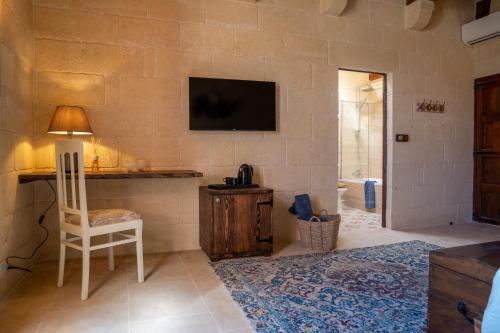 a living room with a chair and a tv on a wall at Home Mood B&B in Għarb