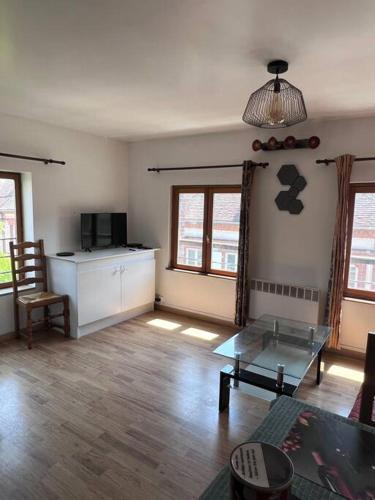 un salon avec une table en verre et une cuisine dans l'établissement Grand Appartement lumineux 2ch. Ville historique., à Verneuil-sur-Avre