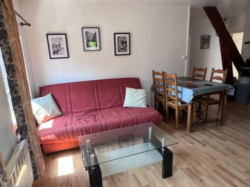 ein Wohnzimmer mit einem roten Sofa und einem Tisch in der Unterkunft Grand Appartement lumineux 2ch. Ville historique. in Verneuil d’Avre et d’Iton