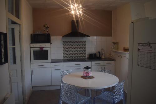 a kitchen with a table and chairs and a refrigerator at havre de paix in Saint-Junien
