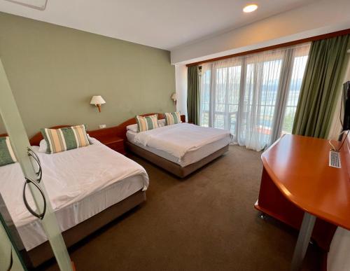 a hotel room with two beds and a desk at Hotel Millennium in Pogradec