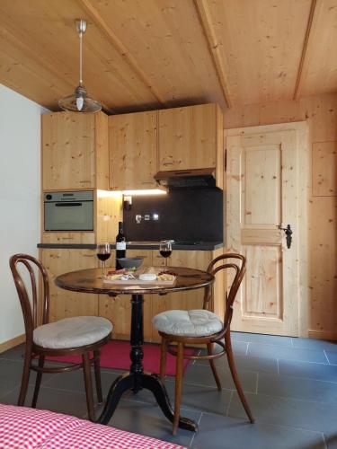 a kitchen with a table and chairs with wine glasses at Chez Pierre in Praz-de-Fort