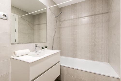 a white bathroom with a sink and a tub at UNIVERSITY & TECH PARK MALAGA APARTMENT in Málaga