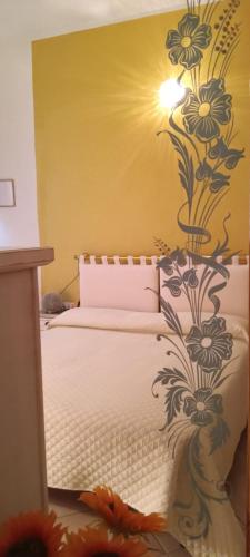 a bedroom with a bed with a flower mural on the wall at Domos Le Due Tuie in Piscinas