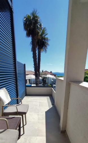 a balcony with two chairs and a palm tree at Beach Hotel Božikovina in Podstrana