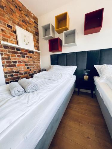 two beds in a room with a brick wall at Apartamenty Żary in Żary