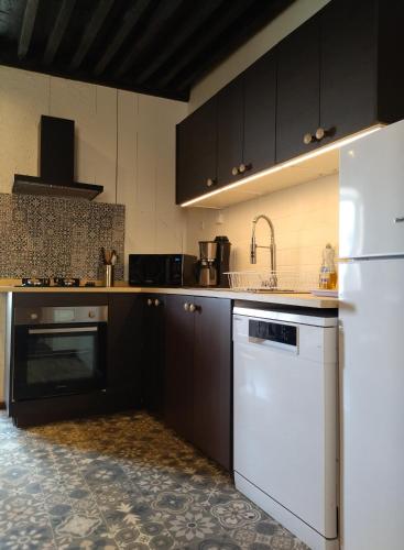 a kitchen with a white refrigerator and a dishwasher at Gîte de la Tournelle in Pradelles