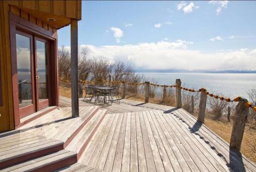 a wooden deck with a table and a view of the water at The Lookout - ALASKA SIZED VIEWS in Homer