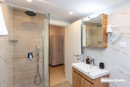 W łazience znajduje się prysznic, umywalka i lustro. w obiekcie Matsas House & Studio w mieście Paleokastritsa