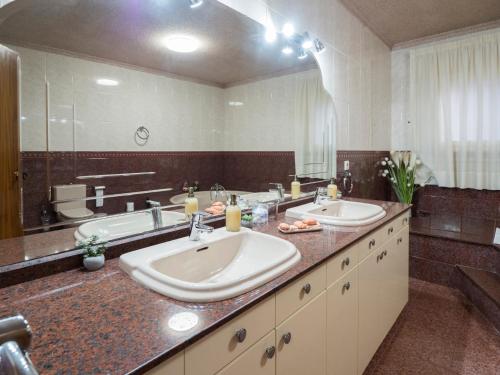 a bathroom with two sinks and a large mirror at MM DELTA HOLIDAYS in El Lligallo del Gànguil