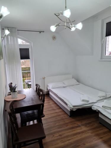 een slaapkamer met een bed, een tafel en een stoel bij Willa Admirał in Trzęsacz