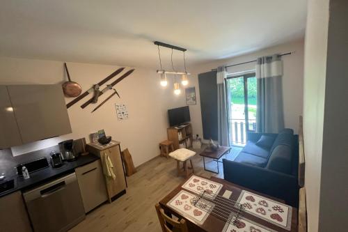 ein Wohnzimmer mit einem blauen Sofa und einer Küche in der Unterkunft Le Granier en Chartreuse in Saint-Pierre-dʼEntremont