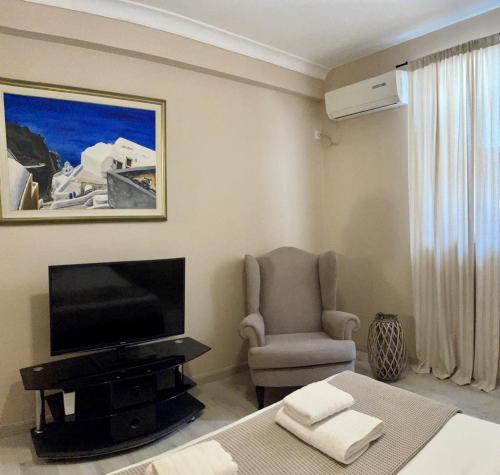 a living room with a tv and a chair and a bed at The Acropolis Cave Apartment in Athens