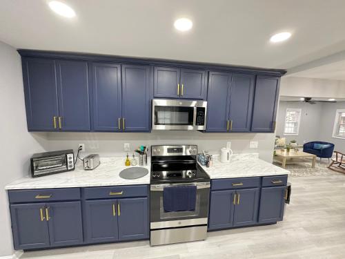 a kitchen with blue cabinets and stainless steel appliances at Cottage in Heart of Colonial Beach, 7 Mins Walk to the Beach in Colonial Beach