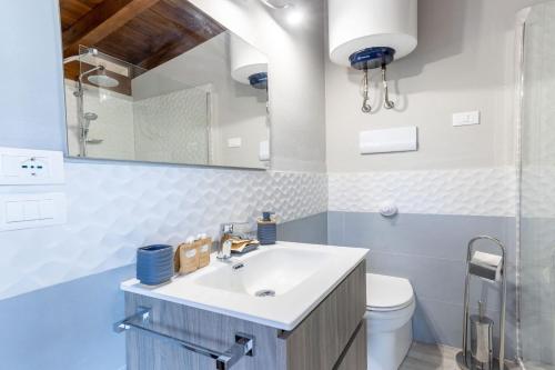 Un baño con lavabo, inodoro y espejo. en Deluxe Sicily Villa, en Buonfornello