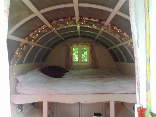 a bed in a small room with a window at Romany Wagon & Cwtch in Llandysul