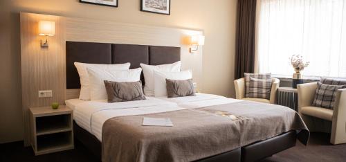 ein Hotelzimmer mit einem großen Bett und einem Stuhl in der Unterkunft Hotel-Restaurant Jagdhaus Heede in Hannoversch Münden