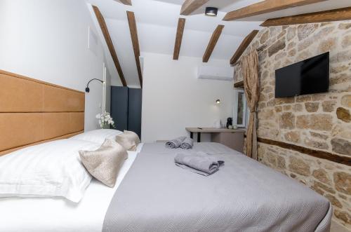 a bedroom with two beds and a tv on a stone wall at Rio Luxury Rooms in Split
