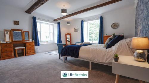 a bedroom with a bed with blue curtains and a desk at The historic Bulls Head-Grade II Listed in Chapel en le Frith