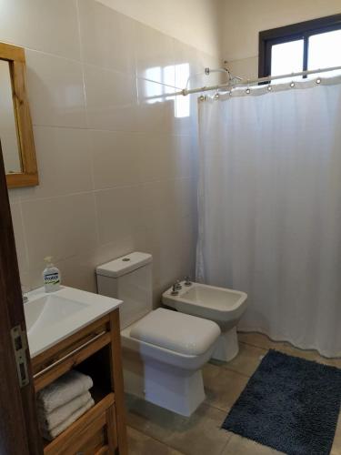 a white bathroom with a toilet and a sink at Finca La Clementina in Tunuyán