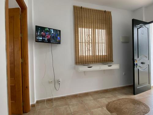 a living room with a television on the wall at Alojamiento Rural Al´Mare in Conil de la Frontera