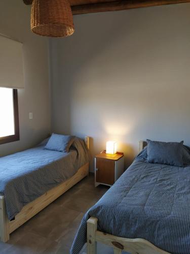 a bedroom with two beds and a table with a lamp at Finca La Clementina in Tunuyán
