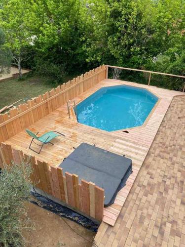 a small swimming pool with a wooden deck and a chair at L’échappée de Vallon in Vallon-Pont-dʼArc