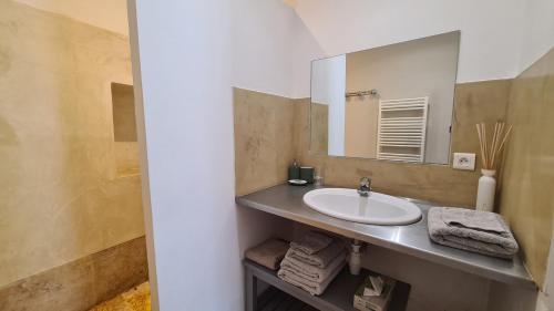 a bathroom with a sink and a mirror at Cocon du Papillon à Lourmarin in Lourmarin