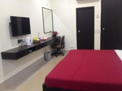 a bedroom with a red bed and a desk with a television at Hotel Nest International in Kolkata
