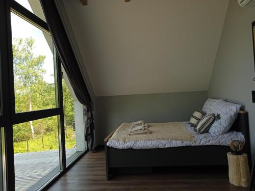 een slaapkamer met een bed en een groot raam bij Lawendowa Stodoła in AdamÃ³w