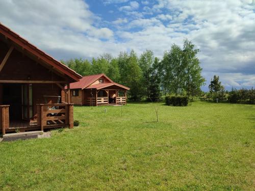 a log cabin in a field next to a field of grass at Domki na zaciszu w Rynie in Ryn