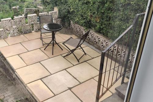 a patio with a table and a chair on it at KINGHORN - Private Room, own entrance, ensuite, sunroom & Views in Kinghorn
