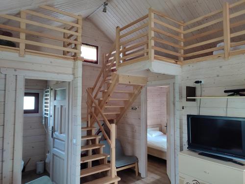 ein kleines Haus mit einer Treppe und einem TV in der Unterkunft Domki na zaciszu w Rynie in Ryn