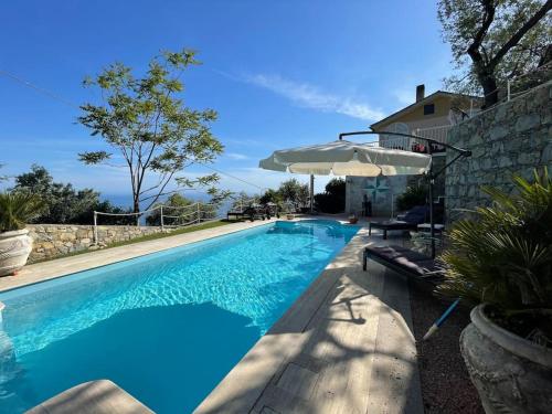 una piscina con sombrilla junto a una casa en Sea South front property1/2acre.Gardens pool hydro, en Pieve Ligure