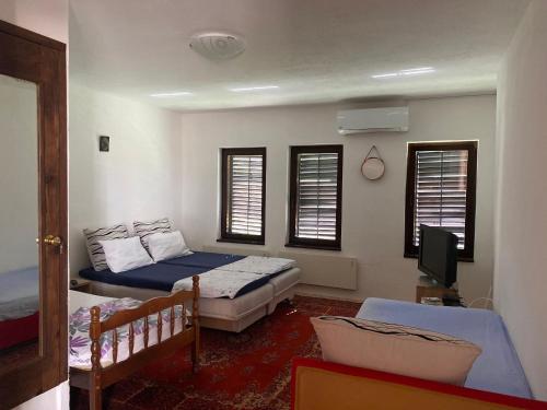 a bedroom with two beds and a tv and windows at Villa San in Blagaj