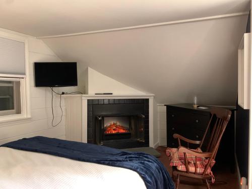 a bedroom with a fireplace and a bed and a television at The Nutmeg Vermont in Wilmington