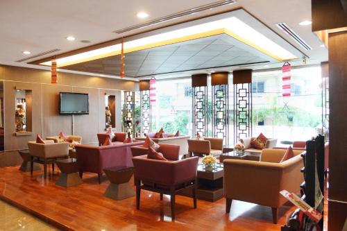 uma sala de espera com sofás e cadeiras e uma televisão em Noppakao Place em Chiang Mai