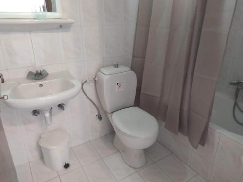 a white bathroom with a toilet and a sink at STUDIO ZOE in Marmari