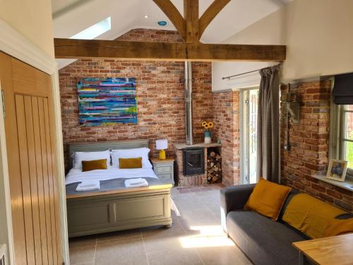 a bedroom with a bed and a couch and a brick wall at Dragonfly cottage in Christchurch