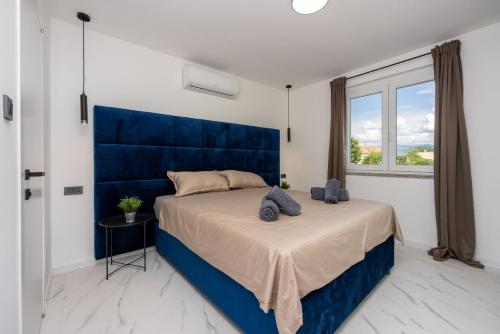 Un dormitorio con una cama grande con cabecero azul. en Villa Velvet, en Baška