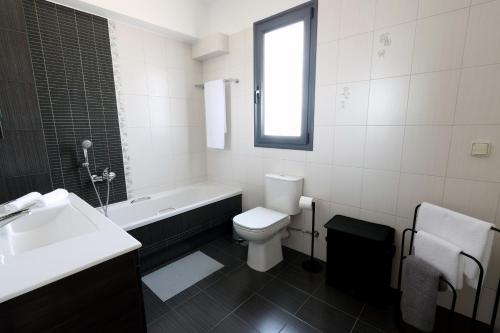 a bathroom with a toilet and a tub and a sink at Thea Apartment_Athens Airport in Spáta